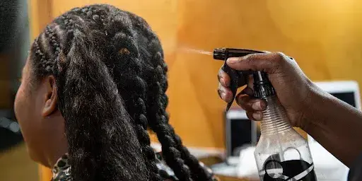 sprinkling water on a girl's hair to loosen tight braids